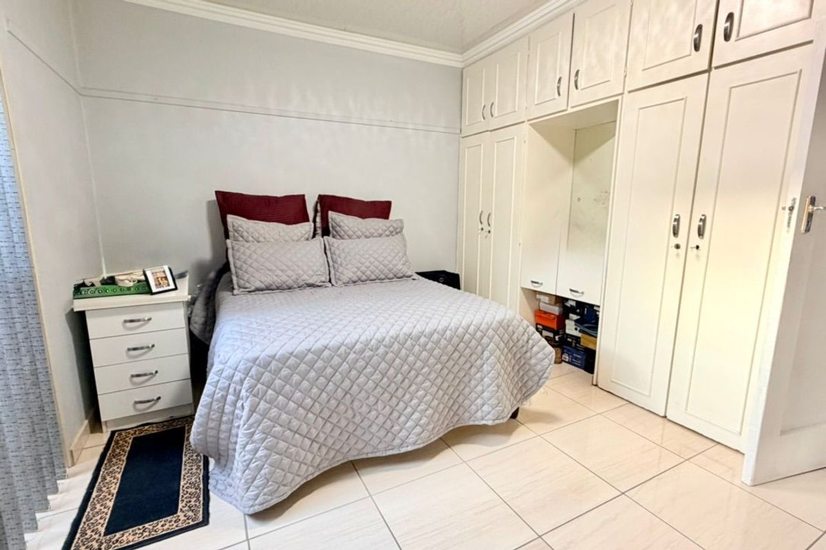 A bedroom featuring tiled flooring, crown molding, and extensive built-in cupboard storage.