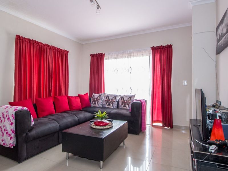 A bright living room featuring tiled flooring and a sliding glass door providing access to the exterior.