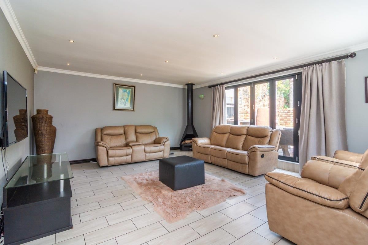 Spacious living room featuring tiled flooring, a modern freestanding fireplace, and large sliding glass doors providing access to the outdoor area.