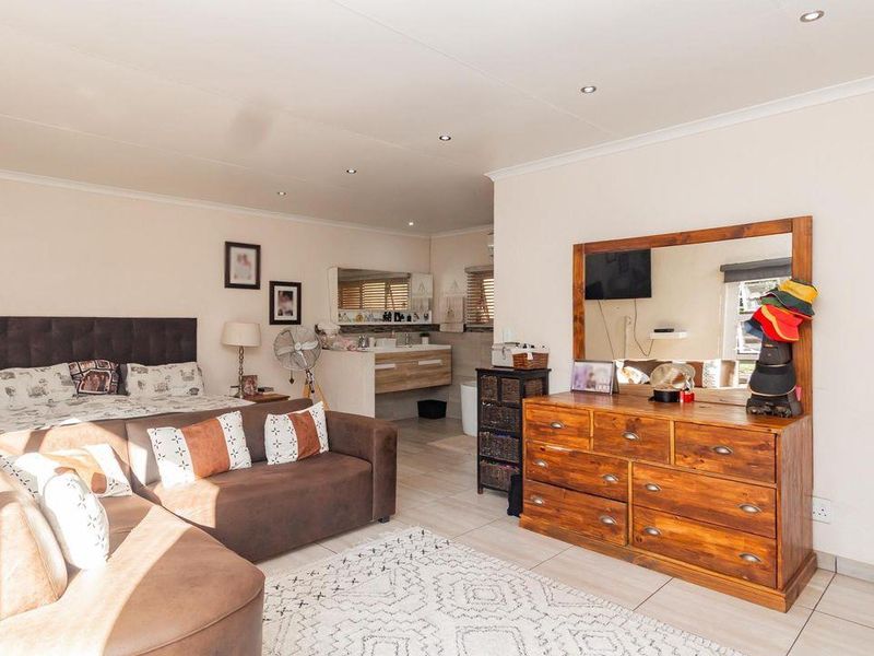 Spacious bedroom featuring tiled flooring, recessed lighting, and an integrated open-plan vanity area with a modern basin.