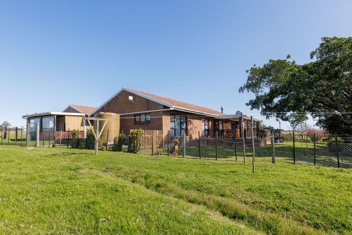 Rear view of a brick-built small holding residence featuring a covered patio area, water storage tank, and fenced garden space.