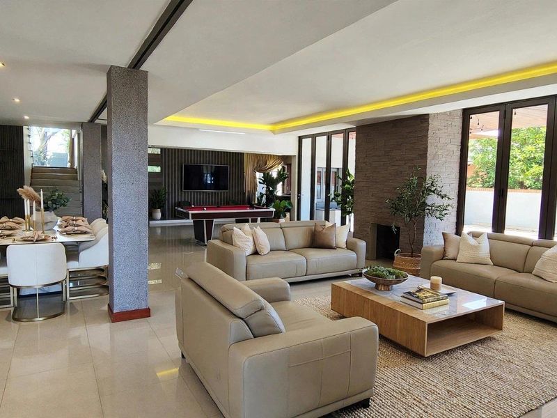 Spacious open-plan living and dining area featuring modern tiled floors, recessed ceiling lighting, a stone feature wall, and large bi-fold doors leading outdoors.