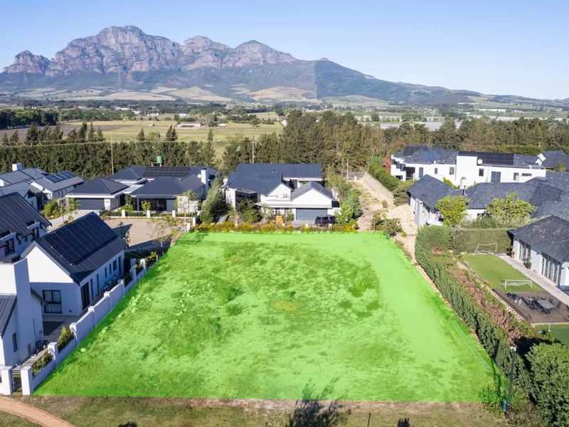 Aerial view of a vacant residential plot in a developed estate, featuring clear boundaries and scenic mountain views.