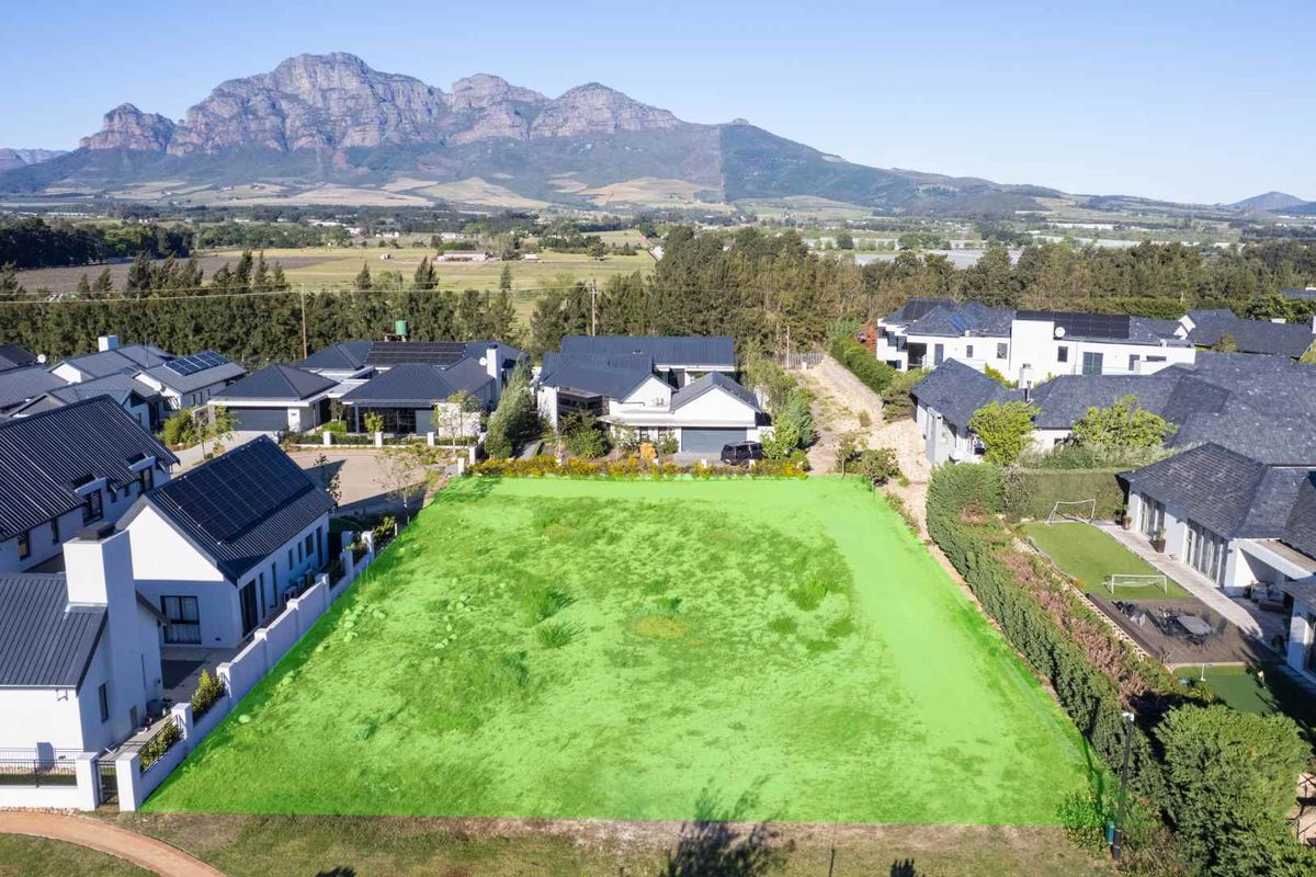 Aerial view of a vacant residential plot in a developed estate, featuring clear boundaries and scenic mountain views.