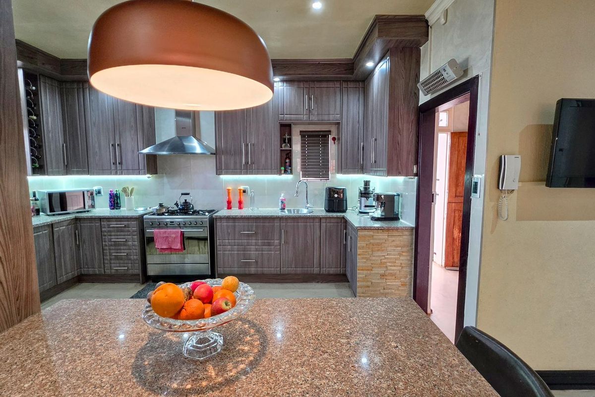 A well-appointed kitchen featuring dark wood cabinetry, granite countertops, stainless steel appliances, and modern under-cabinet lighting, providing a functional and stylish cooking space.