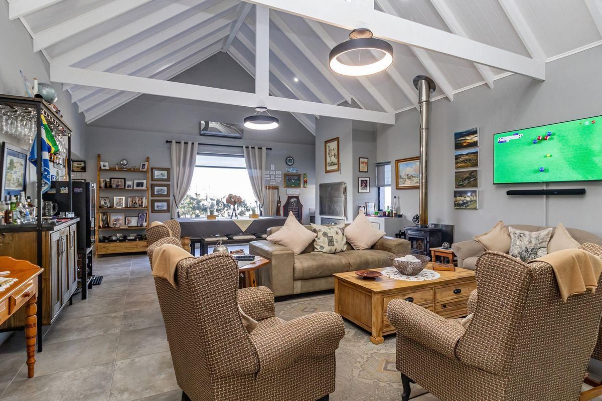 Spacious living room featuring a high vaulted ceiling with exposed beams, tiled flooring, and a cozy wood-burning stove.