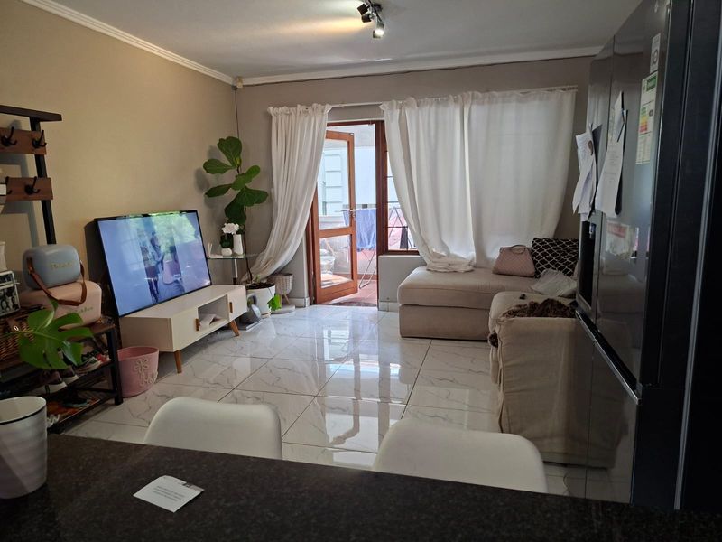 Open plan living area featuring polished tiled flooring and direct access to an outdoor patio through a glass door.