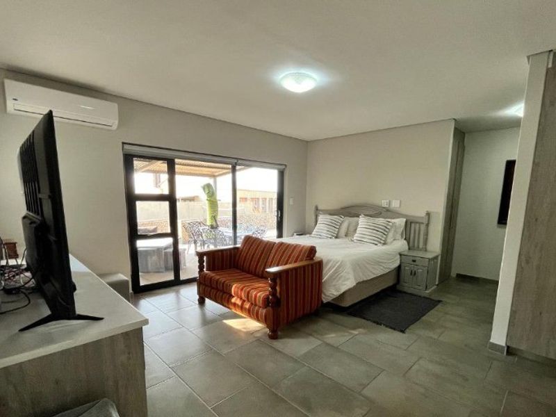 Spacious bedroom featuring tiled flooring, built-in cupboards, an air conditioning unit, and sliding glass doors providing direct access to an outdoor patio area.