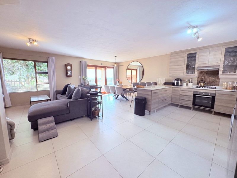 Spacious open-plan living area featuring a modern kitchen with built-in cabinetry, island, and tiled flooring, seamlessly flowing to the dining and lounge space.