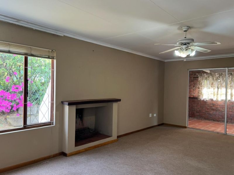 Spacious living room featuring a built-in fireplace, ceiling fan, and sliding door access to an outdoor patio area.