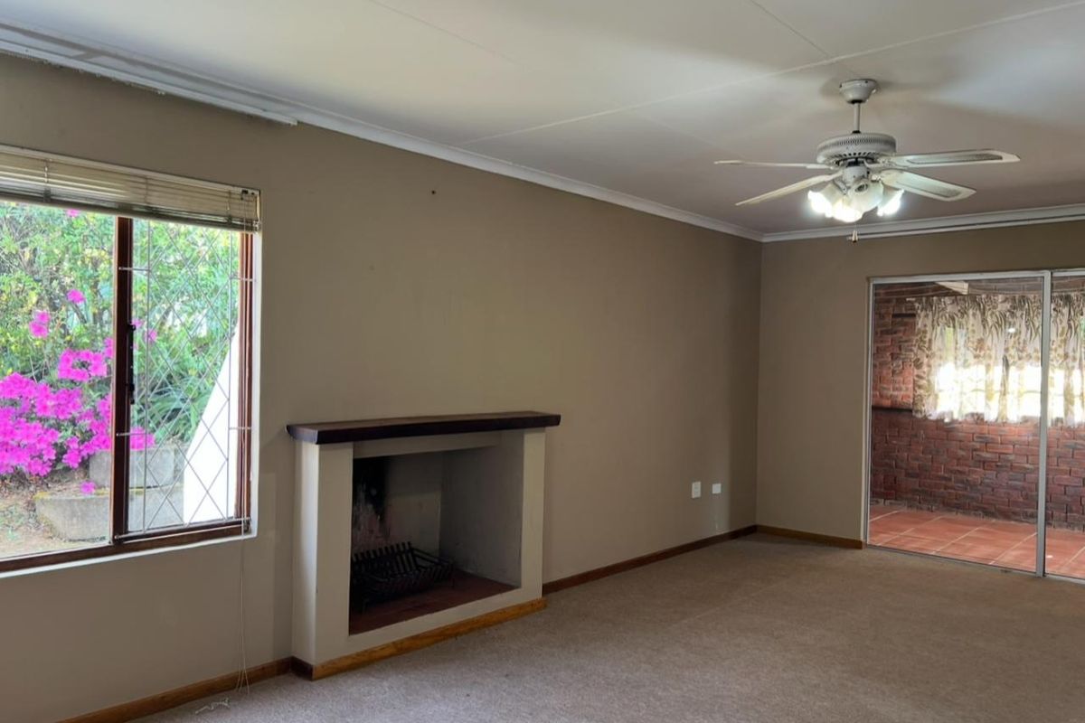 Spacious living room featuring a built-in fireplace, ceiling fan, and sliding door access to an outdoor patio area.