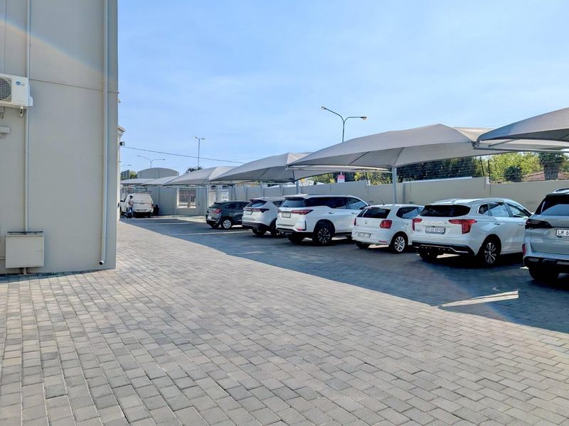 A well-maintained paved parking area featuring multiple shade cloth carports and secure perimeter walling.