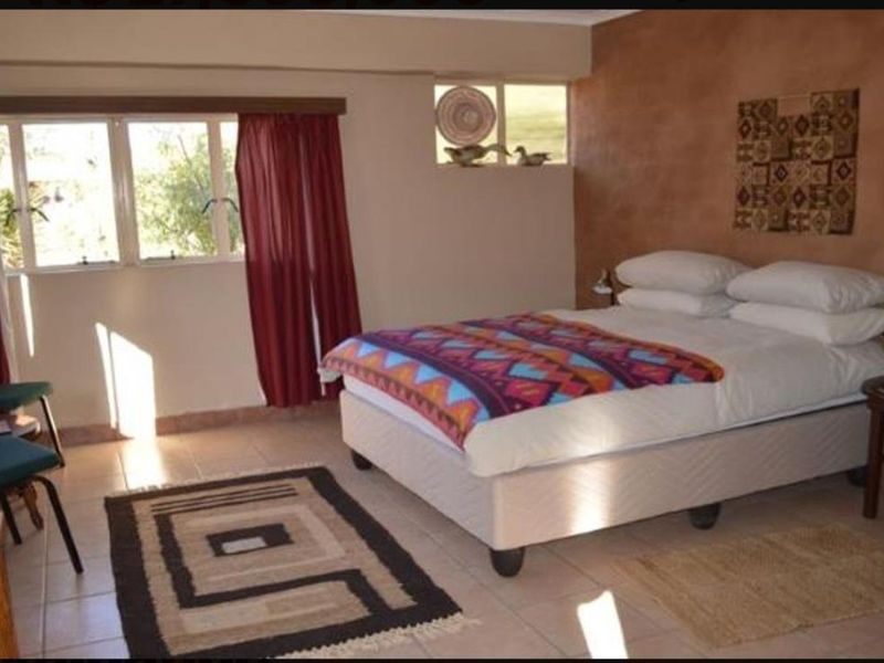 A bedroom featuring tiled flooring, an accent wall, and natural light through casement windows.