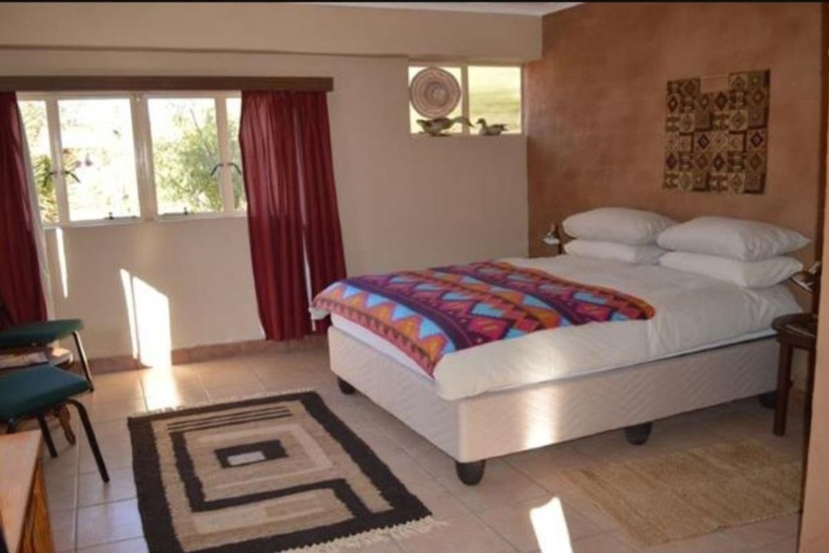 A bedroom featuring tiled flooring, an accent wall, and natural light through casement windows.