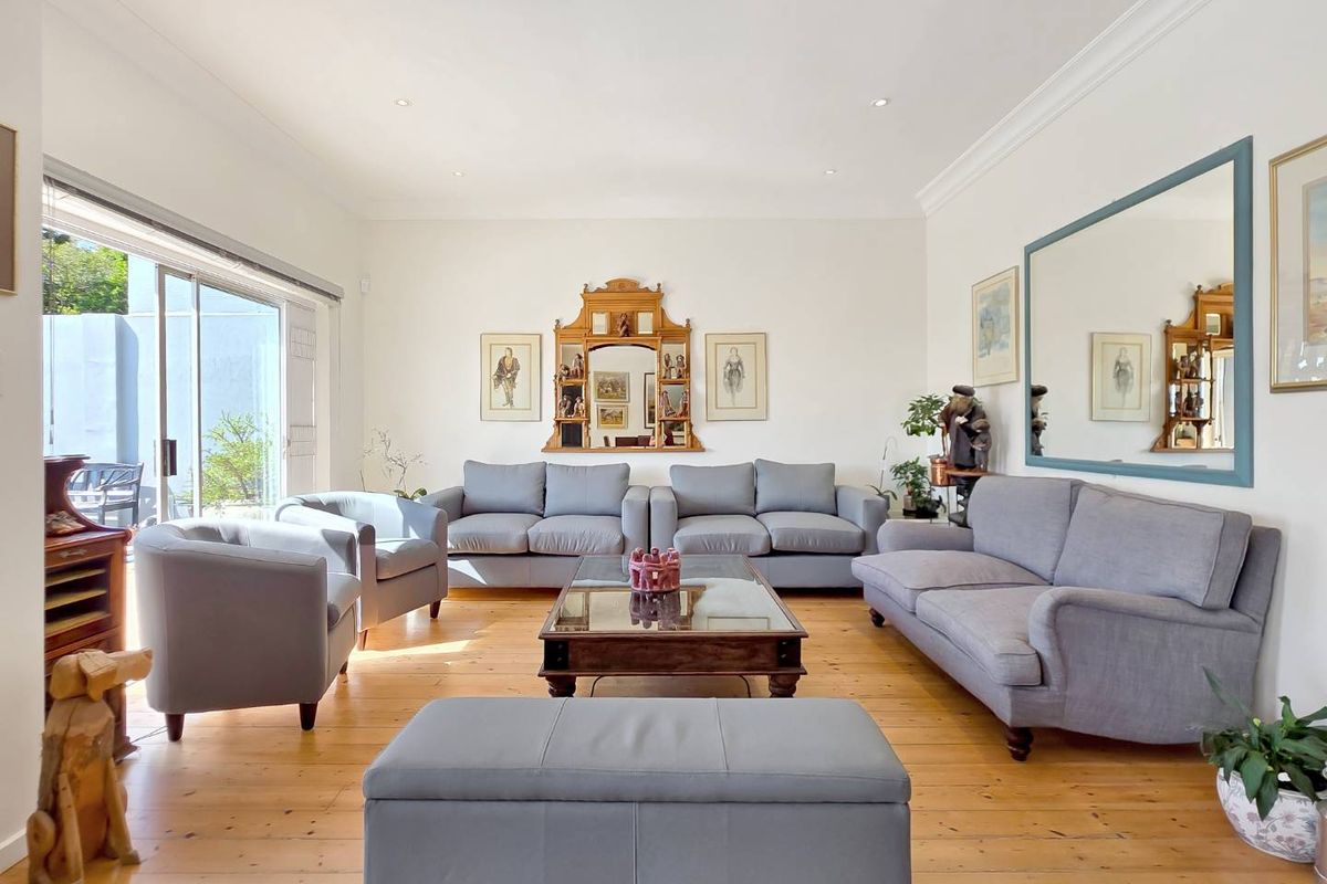 A bright and spacious living room featuring polished timber flooring, recessed downlighting, and large sliding glass doors providing seamless access to the outdoor area.