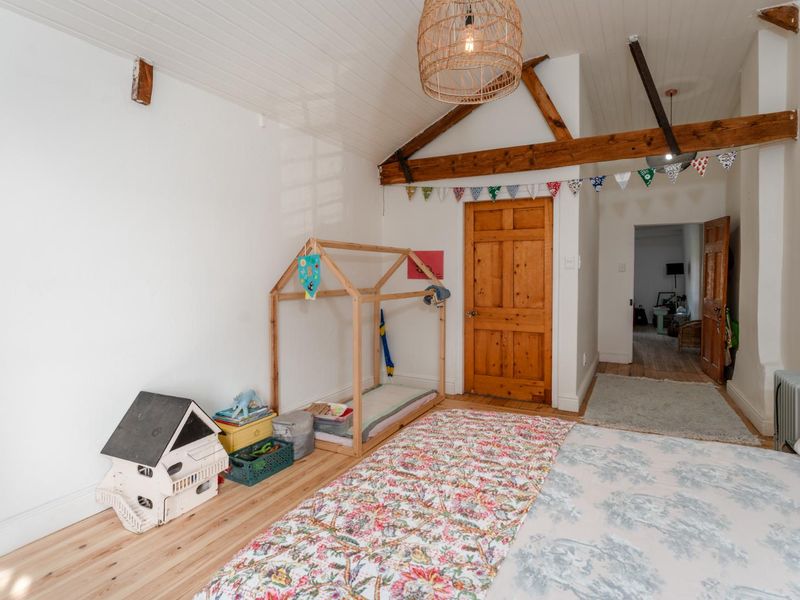 A bedroom featuring exposed timber ceiling beams, a timber panelled ceiling, and timber flooring, creating a warm and rustic atmosphere.