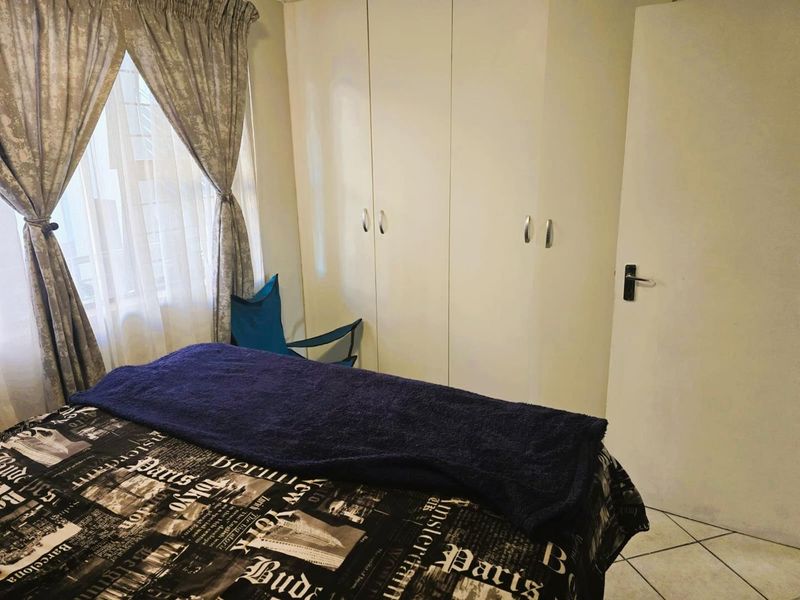 A bedroom featuring built-in cupboards and tiled flooring, offering a functional space with natural light from the window.