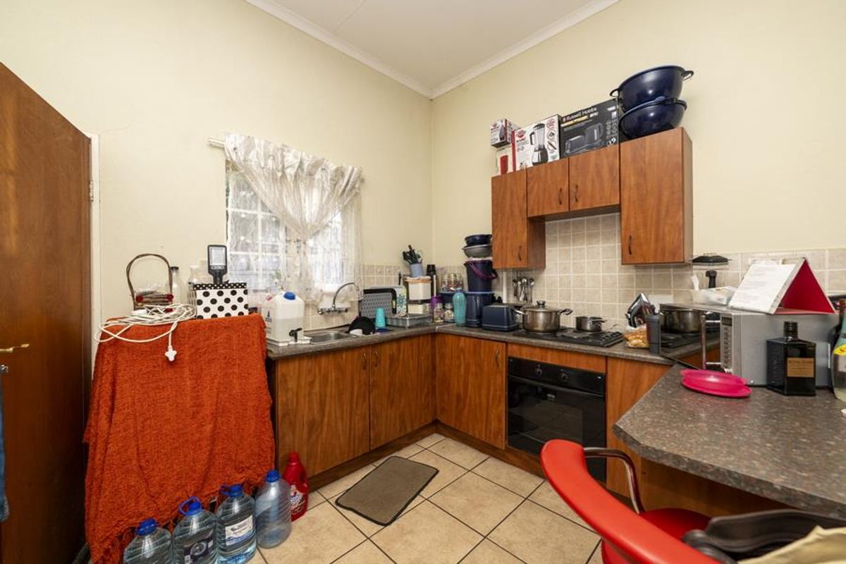 A functional kitchen featuring wood-finish cabinetry, a built-in oven and hob, tiled backsplash, and a breakfast bar area.