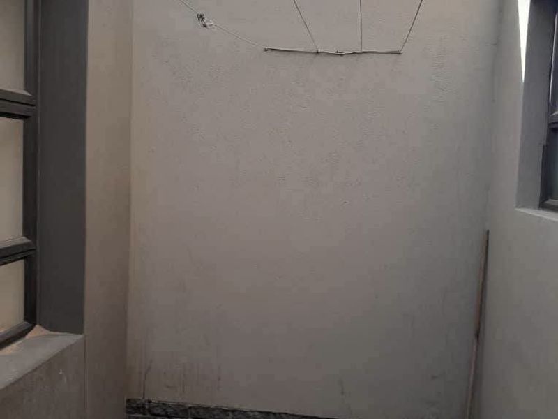 A functional outdoor utility or drying area featuring paved flooring, a drainage point, and a wall-mounted washing line.