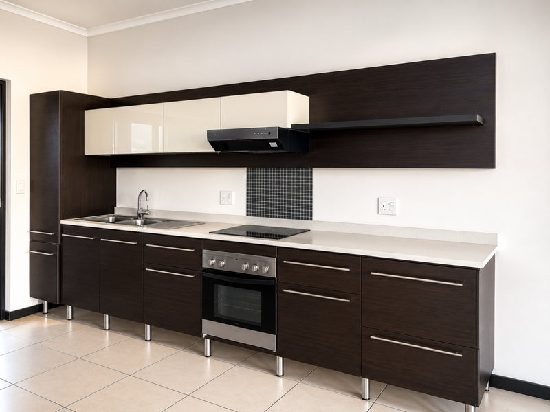 Modern kitchen featuring dark wood cabinetry, contrasting cream upper cabinets, stone countertops, integrated stainless steel appliances, and a mosaic tile splashback.