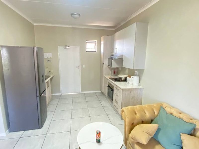 Open plan kitchen and living area featuring tiled flooring, built-in cabinetry, and integrated kitchen appliances.