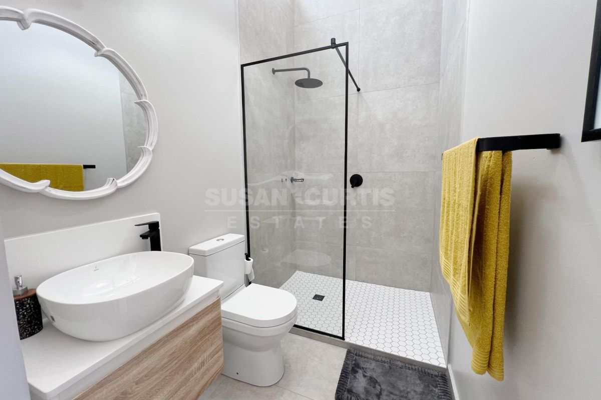 Modern bathroom featuring a walk-in shower with black frame, wall-mounted vanity with vessel sink, and contemporary grey tiling.
