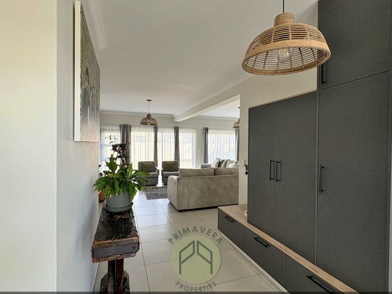 An open-plan living area featuring modern built-in cabinetry, neutral tiled flooring, and large sliding doors that provide ample natural light.