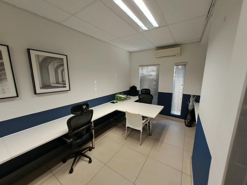 A functional office space featuring tiled flooring, a suspended ceiling with integrated lighting, split-system air conditioning, and venetian blinds.