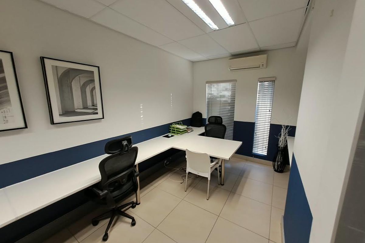 A functional office space featuring tiled flooring, a suspended ceiling with integrated lighting, split-system air conditioning, and venetian blinds.