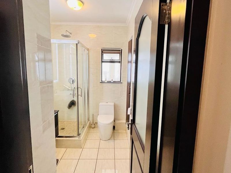 A clean and functional bathroom featuring a glass shower enclosure, ceramic floor tiles, and a modern toilet.