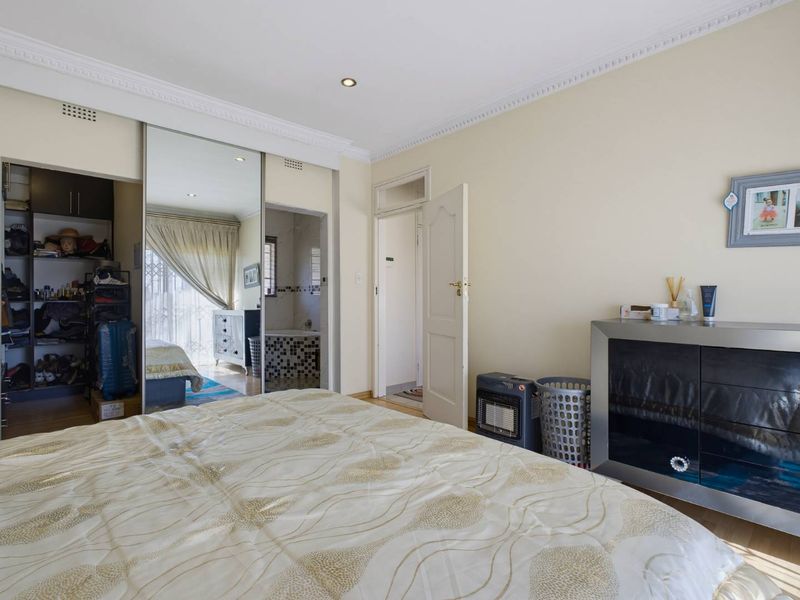 A bedroom featuring laminate flooring, crown molding, recessed lighting, and a built-in mirrored wardrobe with integrated storage space.
