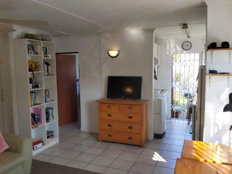 Open plan living area featuring tiled flooring, a ceiling fan, and direct access to an exterior area through a security gate.