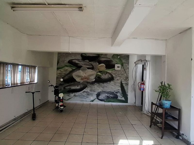 Open-plan office space featuring ceramic tiled flooring, wall-mounted air conditioning, and exposed ceiling beams, suitable for a variety of business configurations.