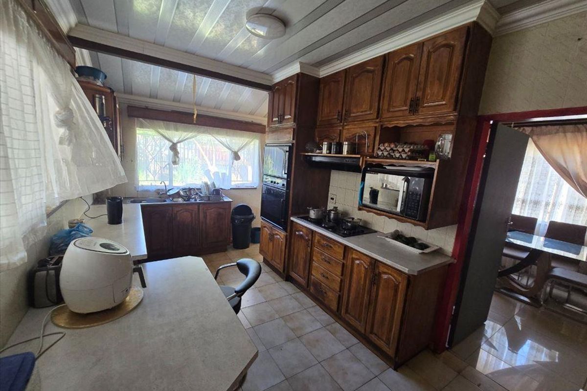 A functional kitchen featuring traditional wooden cabinetry, built-in appliances, and tiled flooring, offering a classic layout with potential for modern updates.