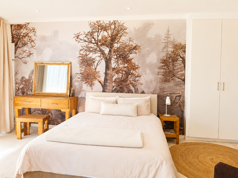 A well-lit bedroom featuring built-in cupboards, neutral tiled flooring, and a decorative feature wall, creating a warm and inviting atmosphere.