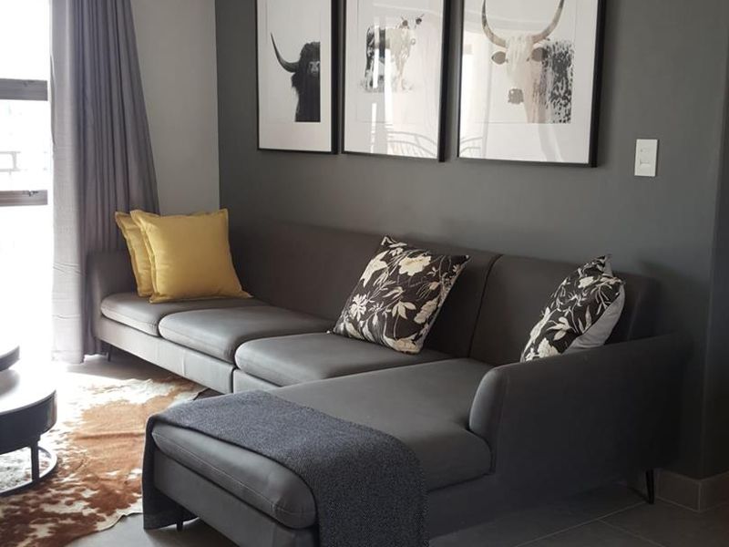 A modern living room featuring large format floor tiles and a dark grey feature wall, creating a contemporary and comfortable atmosphere.
