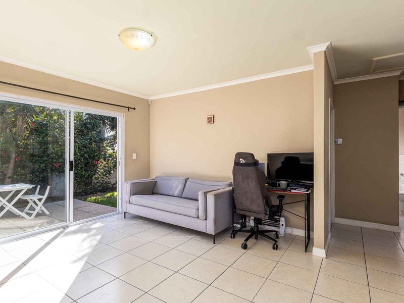 A bright living room featuring ceramic floor tiles and a large sliding glass door providing direct access to the outdoor patio area.