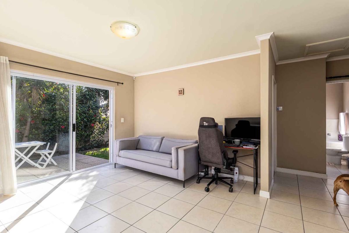A bright living room featuring ceramic floor tiles and a large sliding glass door providing direct access to the outdoor patio area.