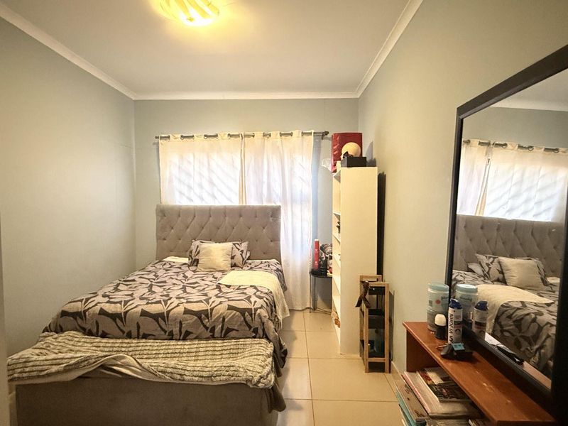 A functional bedroom featuring tiled flooring and neutral wall finishes, providing a comfortable and well-lit sleeping space.