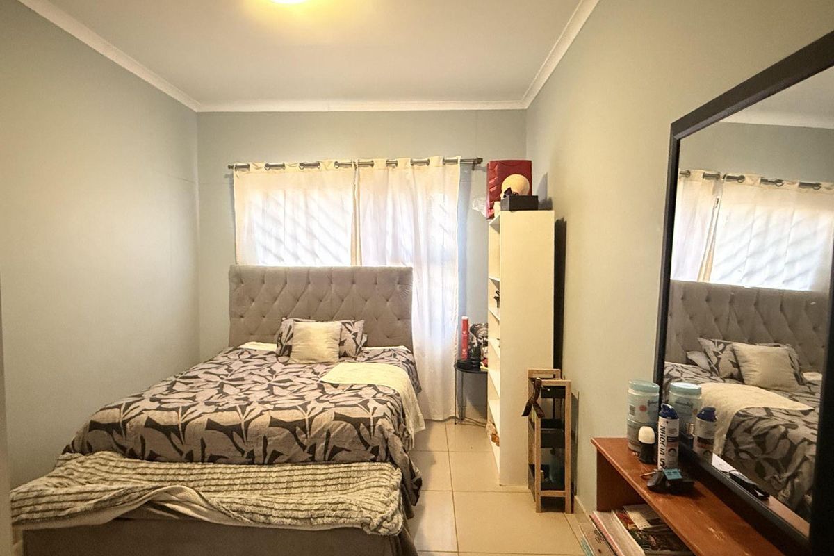 A functional bedroom featuring tiled flooring and neutral wall finishes, providing a comfortable and well-lit sleeping space.