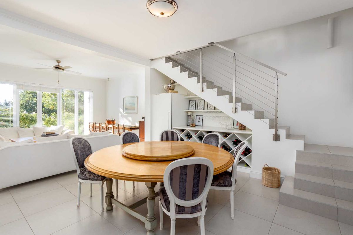 Open plan dining area featuring a modern staircase with stainless steel balustrade and integrated under-stair wine storage.