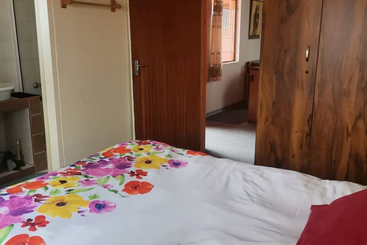 A bedroom featuring wooden doors and access to an adjoining bathroom, with a view into the adjacent room.