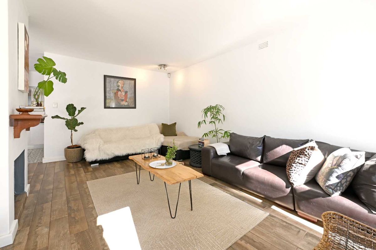 A bright living room featuring wood-look flooring and a built-in fireplace, offering a comfortable and inviting space for relaxation.