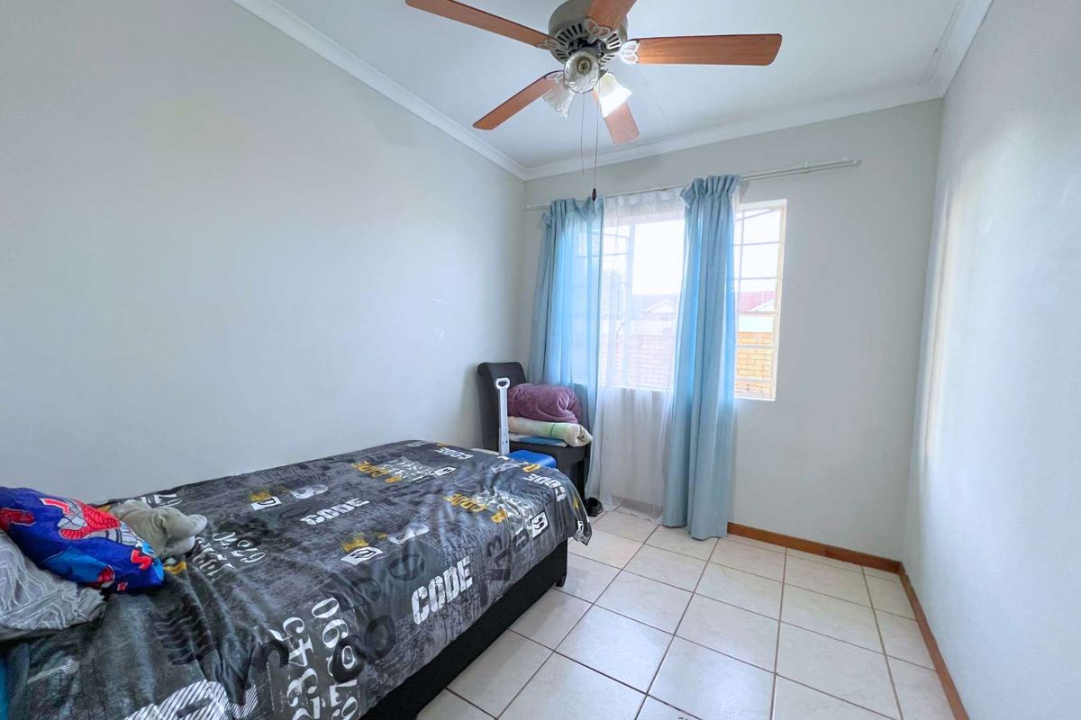 A functional bedroom featuring tiled flooring, a ceiling fan, and a window with natural light.