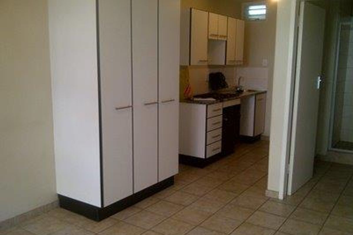 A compact kitchen area featuring built-in cabinetry, tiled flooring, and essential cooking fixtures, presented in a clean, vacant state.