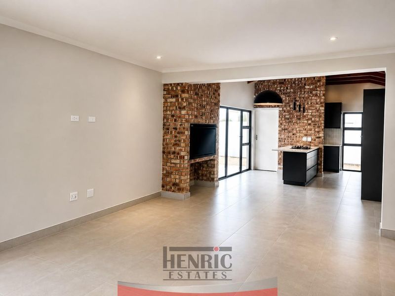 Spacious open-plan living and kitchen area featuring modern tiled floors, exposed brick accents, and a functional kitchen island with a built-in gas hob.