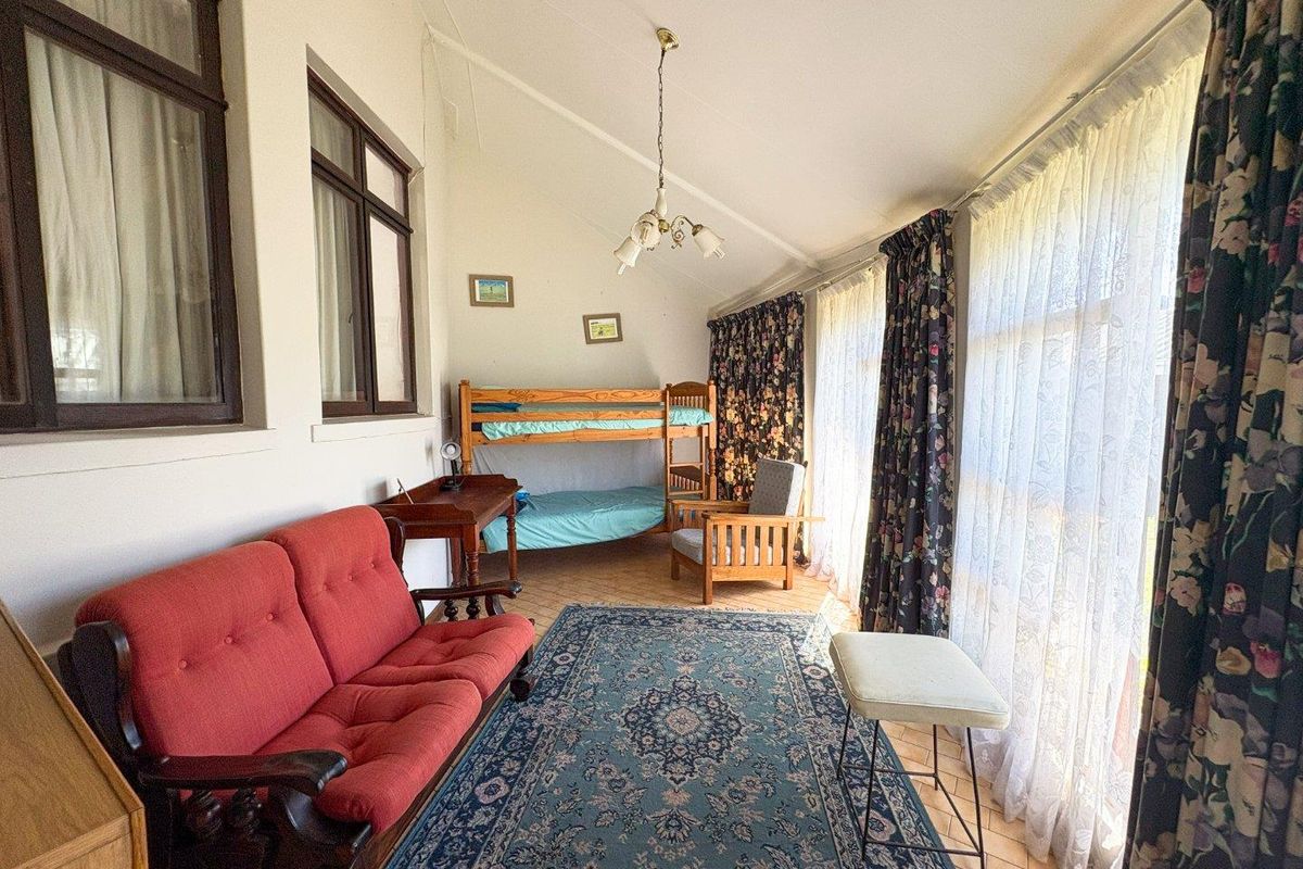 A spacious bedroom featuring tiled flooring, a vaulted ceiling, and large windows that provide ample natural light.