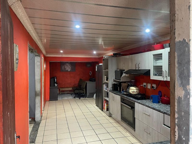A functional kitchen featuring built-in cabinetry, a gas hob, and an integrated oven, with tiled flooring and recessed lighting throughout the space.