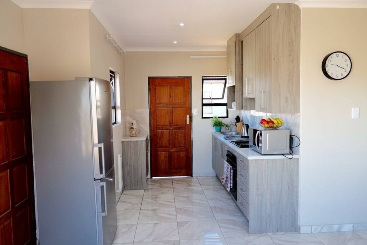 A modern kitchen featuring light wood-grain cabinetry, tiled flooring, and integrated appliances, offering a clean and functional workspace.