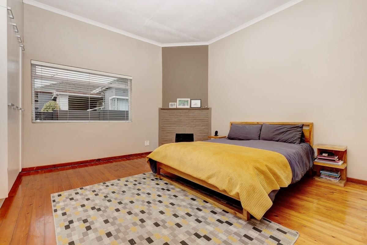 A bedroom featuring original timber flooring, a built-in fireplace, and integrated cupboard storage.